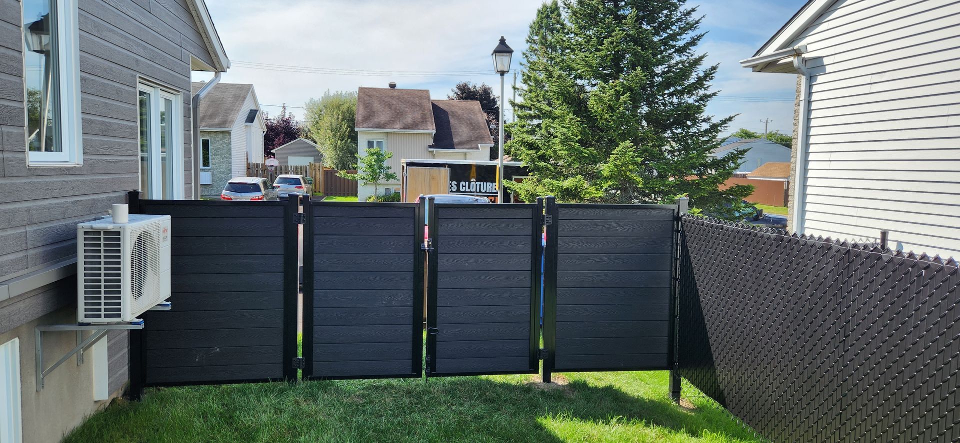 Black composite privacy fence with an aluminium frame and matching gate in a Quebec backyard