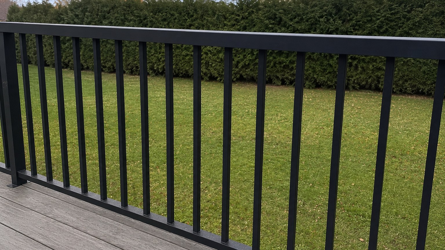 Close-up of a black aluminum guard showing the even gaps between straight vertical pickets under a solid top rail